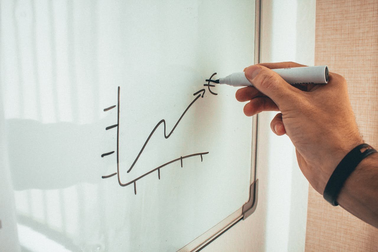 Crop man drawing on whiteboard during financial training